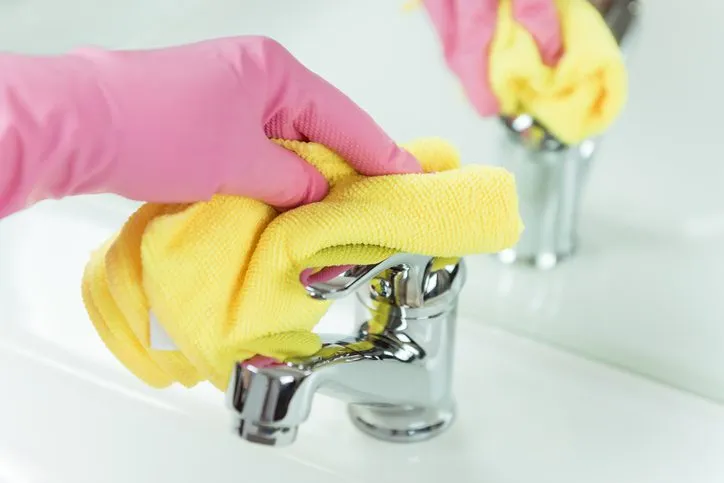 House cleaner wiping down bathroom faucet